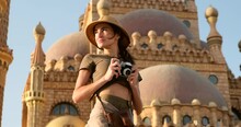 A Slender Girl, A Tourist, Travels Alone In The Eastern Countries Of The Persian Gulf, In Short Tourist Shorts, A Shirt And A Discovery-style Felt Hat, Takes A Photo Of The Old Temple
