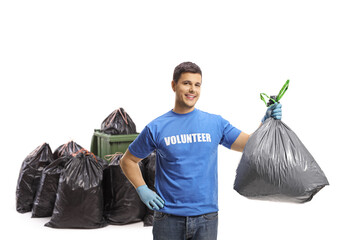 Poster - Male volunteer holding a plastic garbage bag in front of bins