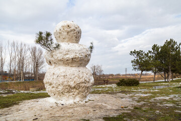 Wall Mural - Huge spring snowman in melted meadow. Background with copy space for lettering or text