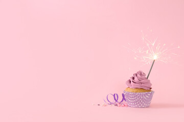 Wall Mural - Birthday cupcake with burning sparkler, streamer and sprinkles on pink background. Space for text