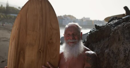 Wall Mural - Senior surfer holding surf board on the beach at sunset - Concept of joyful elderly person and extreme sport