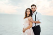 © omelnickiy - young couple a guy in black breeches and a girl in a pink dress are walking along the white sand