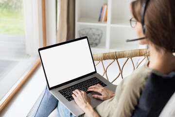 Wall Mural - Young woman working at home, Student girl wearing headset using laptop computer with empty white blank screen, meeting online, web conference, studying, e-learning, technology concept