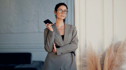 Portrait of a lawyer businesswoman with glasses of European appearance. In a modern office, the workplace is a coworking space. copy space. A finance assistant is talking to a colleague on the phone.