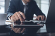 © tippapatt - Businessman using digital tablet and working on laptop computer at office, close up