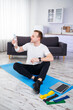 © DSMT - The man goes in for sports at home. Athlete drinks water while sitting on the floor at home, healthy lifestyle