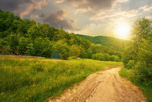 Dirt Road Through Forested Countryside At Sunset. Beautiful Summer Rural Landscape In Mountains. Adventure In Nature Scenery In Evening Light