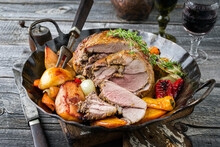 Traditional French Leg Of Lamb With Vegetable And Fruits Served As Close-up In A Rustic Wrought-iron Pan
