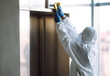 © maxbelchenko - Cleaning and disinfection of the elevator to prevent COVID-19. Man in Hazmat suit, protective gloves and goggles disinfect  buttons of the lift. Covid-2019.