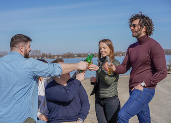 Group of friends at the beach enjoying drinks, toasting to good weekend. 