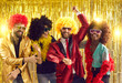 © Studio Romantic - Happy people dancing gangnam style on stage with shiny golden background. Group of friends disguised in boas, glasses, sequin jackets and funny silly curly wigs having fun at night club disco party