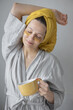 © MyJuly - young and beautiful caucasian woman with patches under her eyes to protect and moisturize the skin and facial skin care, smiling and drinking coffee or tea from a yellow cup, online detox