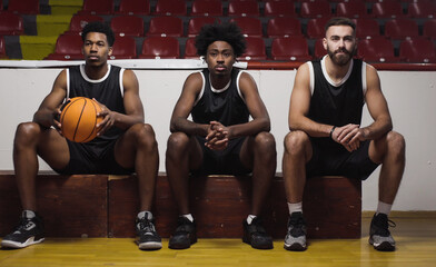 Three basketball players sitting on a bench watching the game