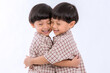 © kanpisut - Twin boys hugging  on white background. Portrait of little son hugging brother or friend. I missing you. Full length happy boy embracing glad brother or friend while standing indoor. Positive meeting