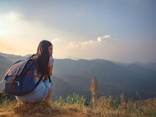 Wall Mural - backside of woman with backpack sitting to enjoy on mountains peak in the morning