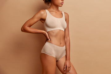 sideways shot of slim woman wears cropped top and panties demonstrates perfect figure after weigh lo