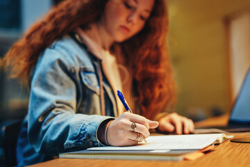 Wall Mural - Young student writing notes at library desk