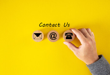 Contact Us, Customer support concept. Wooden cubes with mail, phone and email icons on table, yellow background.