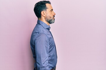 Middle age man with beard and grey hair wearing business clothes looking to side, relax profile pose with natural face with confident smile.