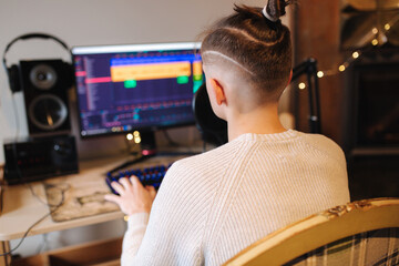 Young happy dj man wearing headphones and working at home while making podcast recording for online show. Back view