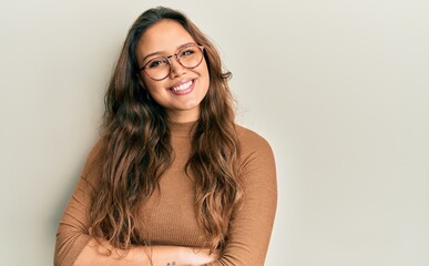 Poster - Young hispanic girl wearing casual clothes and glasses happy face smiling with crossed arms looking at the camera. positive person.