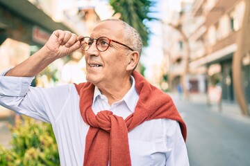Wall Mural - senior man smiling happy wearing glasses walking at the city.
