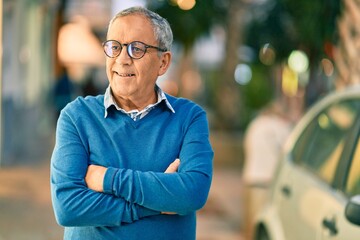Wall Mural - senior grey-haired man with arms crossed smiling happy standing at the city.