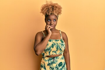 Wall Mural - Young african woman with afro hair wearing summer dress looking stressed and nervous with hands on mouth biting nails. anxiety problem.