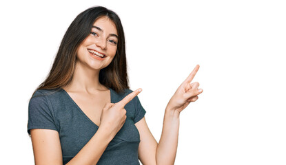 Poster - Young beautiful teen girl wearing casual crop top t shirt smiling and looking at the camera pointing with two hands and fingers to the side.