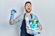 © Krakenimages.com - Young hispanic man holding cleaning products and cockroach angry and mad screaming frustrated and furious, shouting with anger looking up.