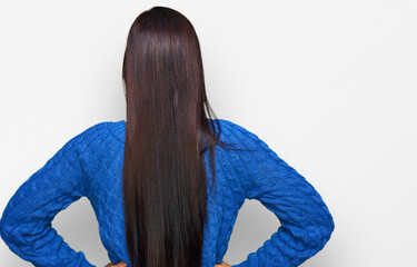 Young hispanic woman wearing casual clothes standing backwards looking away with arms on body