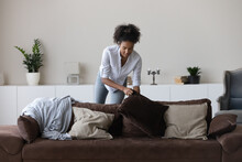 Young African American Woman Clean Cozy New Modern Apartment Or House On Weekend Day. Millennial Biracial Female Renter Or Tenant Decorate Design Comfortable Couch In Living Room At Home.