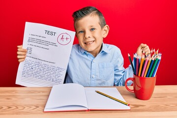 Wall Mural - Adorable caucasian kid holding passed test sitting on the table screaming proud, celebrating victory and success very excited with raised arm