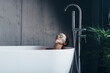 © undrey - Young woman lies in the bathtub with a mask and cucumbers on her face