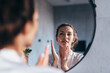 © undrey - Woman washes in front of the mirror, applying foam to her face