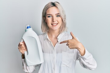 Sticker - Young blonde girl holding detergent bottle pointing finger to one self smiling happy and proud