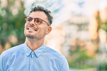 Young hispanic businessman smiling happy standing at the city.