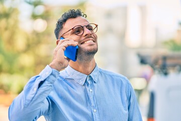 Young hispanic businessman smiling happy talking on the smartphone at the city.