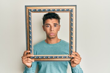 Poster - Young handsome african american man holding blank empty banner depressed and worry for distress, crying angry and afraid. sad expression.