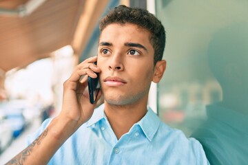 Poster - Young latin man with serious expression talking on the smartphone at the city.