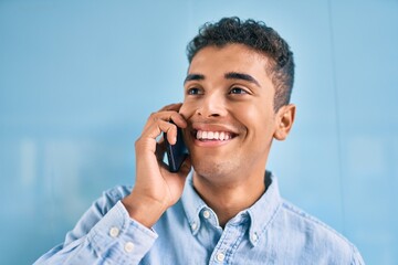 Poster - Young latin man smiling happy talking on the smartphone at the city.