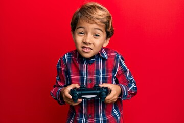 Wall Mural - Adorable latin kid playing video game holding controller clueless and confused expression. doubt concept.