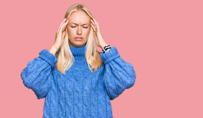 Wall Mural - Young blonde girl wearing wool winter sweater suffering from headache desperate and stressed because pain and migraine. hands on head.