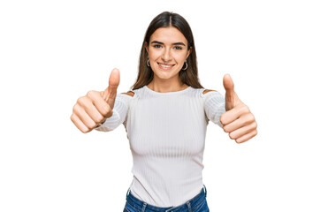 Young hispanic woman wearing casual clothes approving doing positive gesture with hand, thumbs up smiling and happy for success. winner gesture.