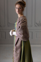 A young Regency woman wearing a green shot silk dress and a paisley shawl 