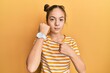 © Krakenimages.com - Beautiful brunette little girl wearing casual striped t shirt in hurry pointing to watch time, impatience, looking at the camera with relaxed expression