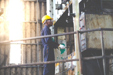 Wall Mural - Young black male engineer..checking checking and repair the machine in Heavy Industry Manufacturing Facility. Service and Maintenance of factory machinery. American African people.