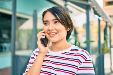 Young latin girl smiling happy talking on the smartphone at the city