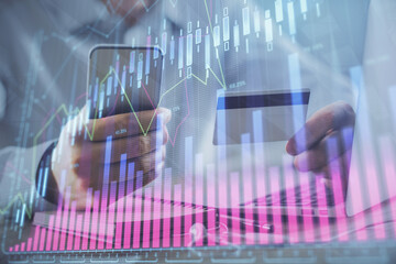 Double exposure of man hands holding a credit card and Forex graph drawing. Stock trading and digital fintech in Internet E-commerce concept.