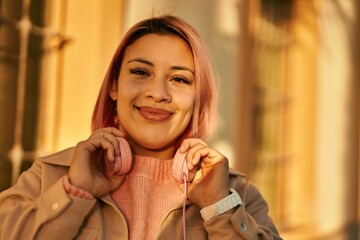 Young hispanic girl smiling happy using headphones at the city.